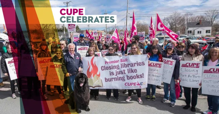 Group shot of workers holding CUPE signs supporting public libraries and big black dog