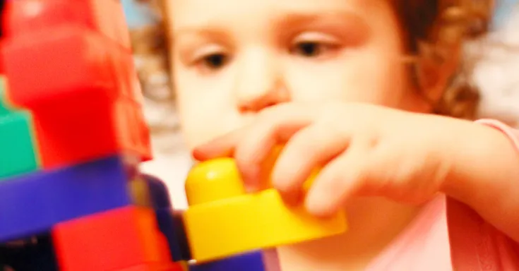 Young child stacks colourful bricks