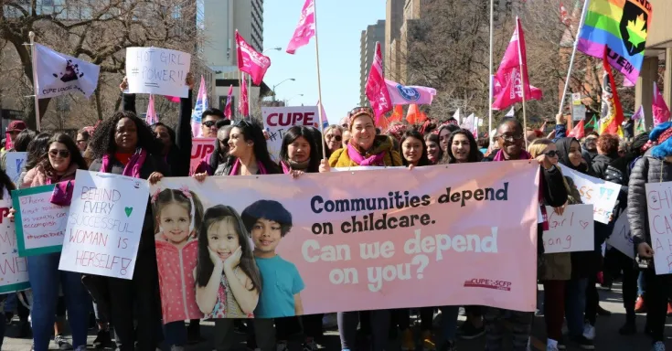 Marchers hold a banner that says Communities depend on childcare - can we depend on you?