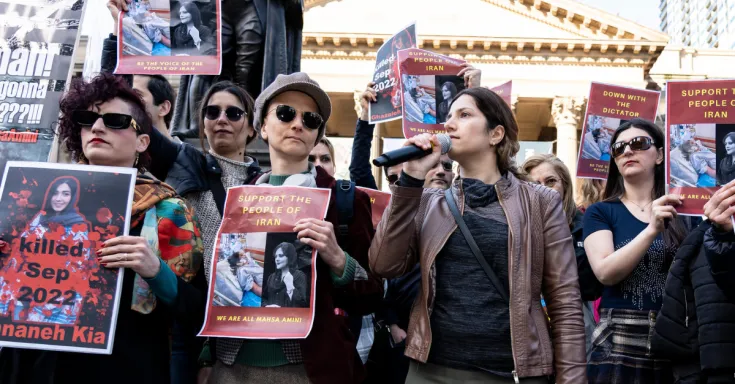 Group of women holding signs and talking on a microphone at a protest