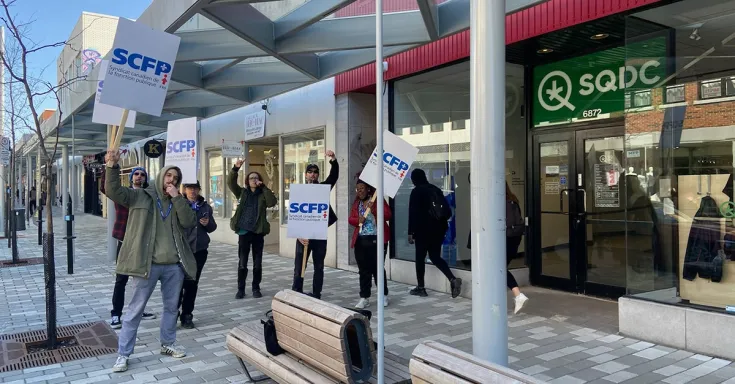People standing in front of SQDC building with picket signs