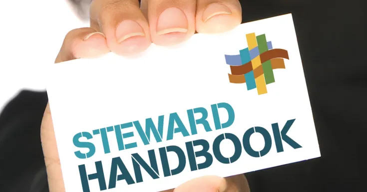Person holding up card that says Steward Handbook